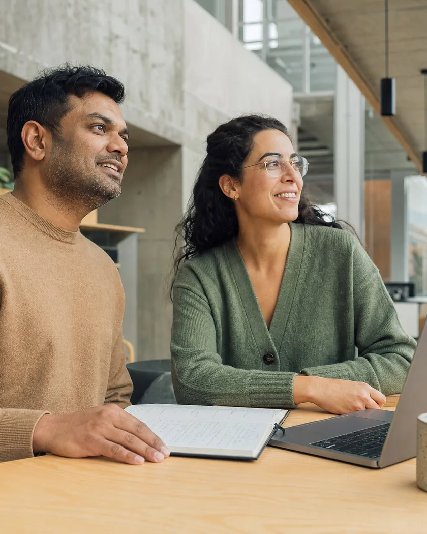 Two experts collaborating over a laptop in a bright workspace